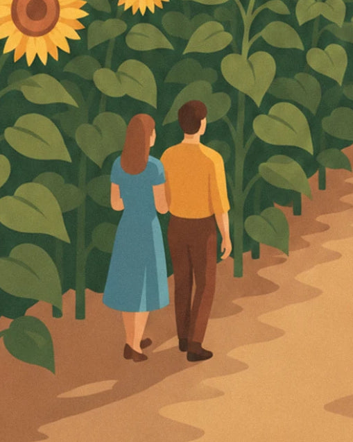 The couple seen from behind, in a blue dress and yellow jumper, on the dirt path between the sunflowers