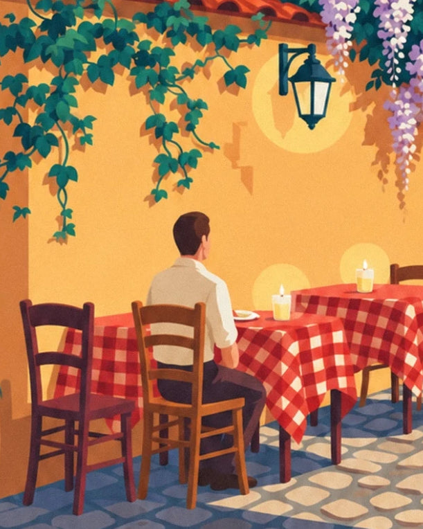 A man seated at a table among wooden chairs, red-checked tablecloths and a lantern