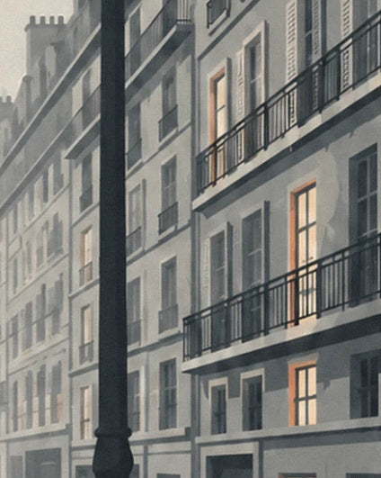 Grey building façades with wrought-iron balconies, orange-lit windows and a black lamppost