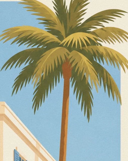 The long green and golden fronds of a palm tree against the blue sky of Nice