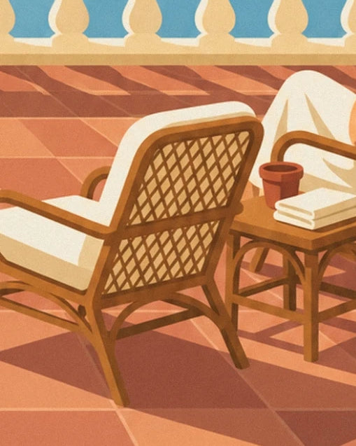 A rattan armchair with a cream cushion, a side table and a terracotta pot on the orange tiles