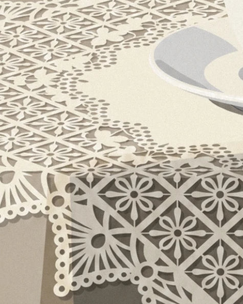 La nappe en dentelle crème aux motifs fleuris, sous le bord de la soucoupe
