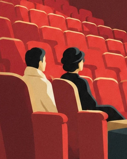 The 2 audience members in beige and black coats among the rows of red seats