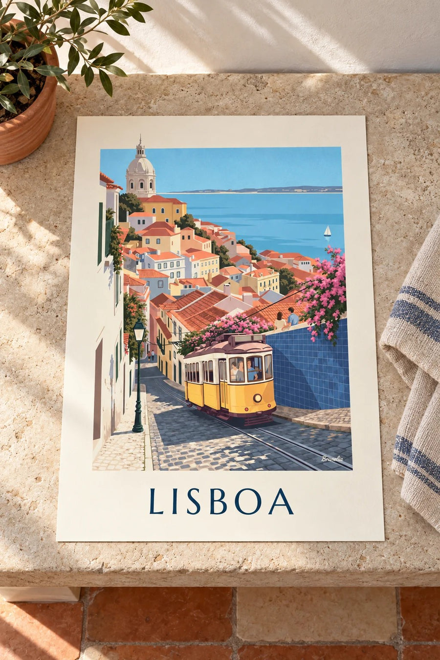 Poster gelbe Straßenbahn in einer Kopfsteinpflastergasse in Lissabon mit Blick auf den Tejo: flach auf einem Tisch