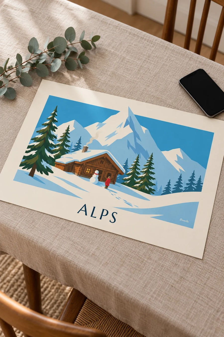 Affiche chalet enneigé et bonhomme de neige dans les Alpes : posée sur une table